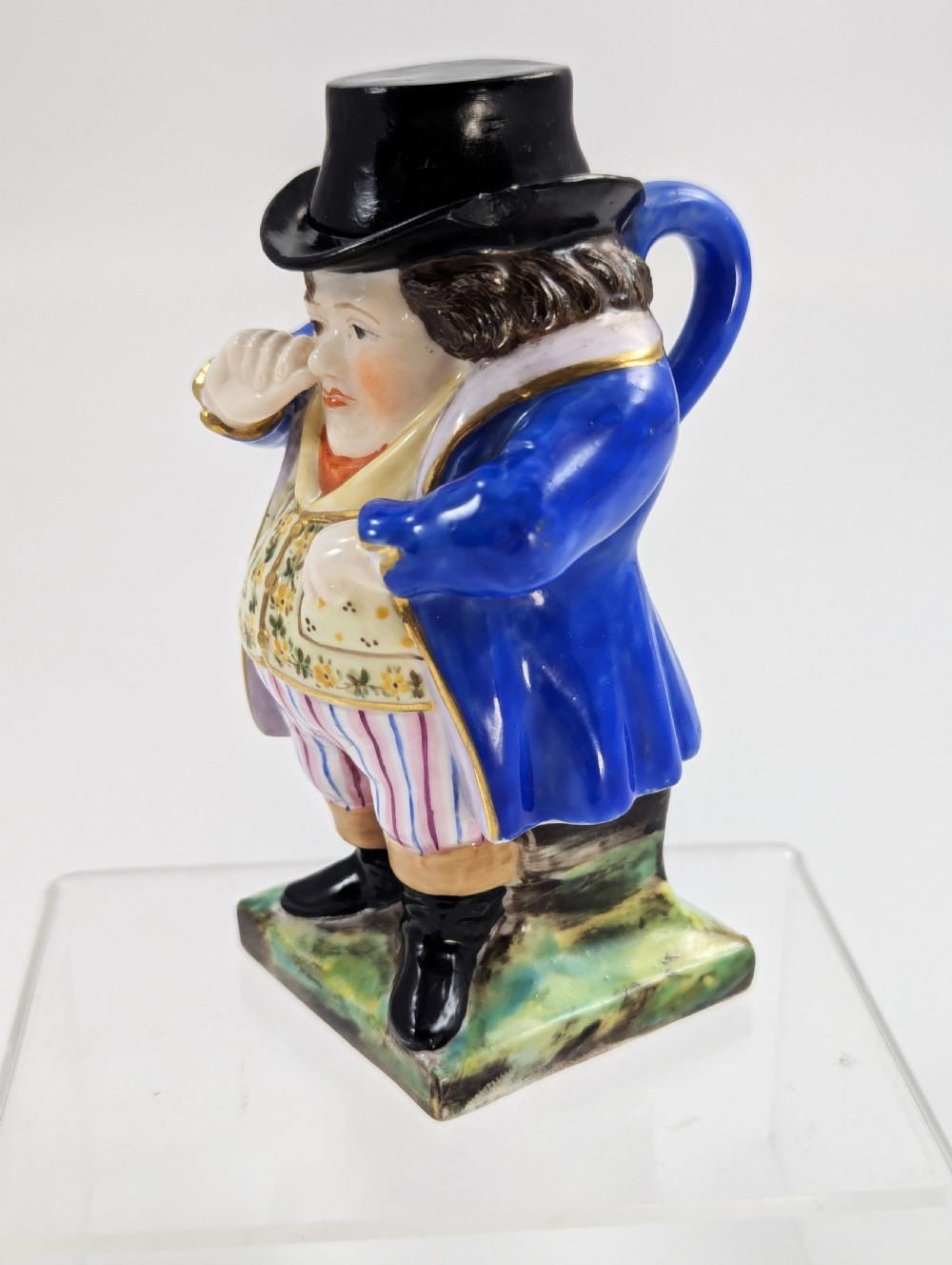 A porcelain Toby jug depicting a gentleman in a black top hat, blue coat, and striped trousers taking snuff. View II
