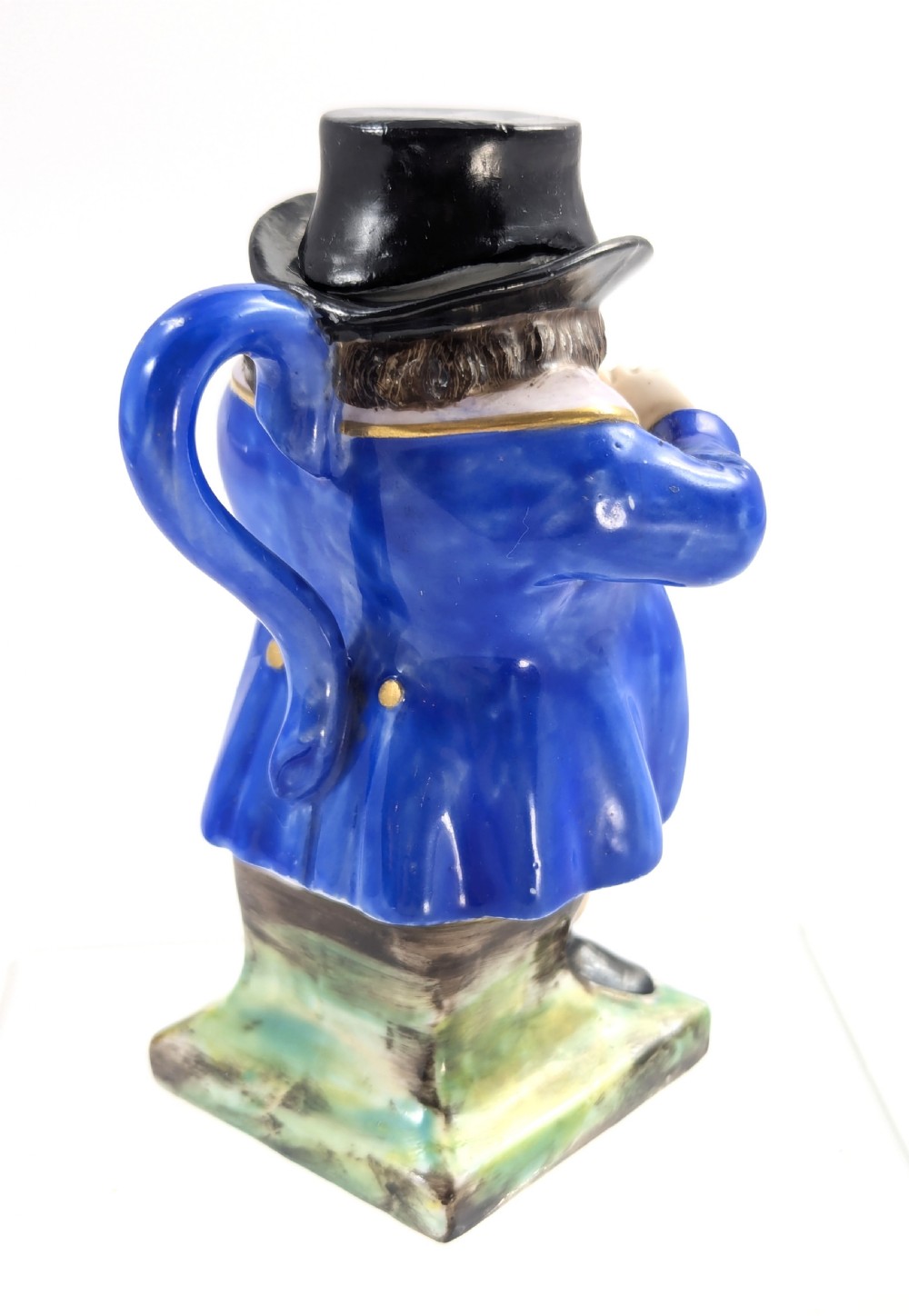A porcelain Toby jug depicting a gentleman in a black top hat, blue coat, and striped trousers taking snuff. View IV