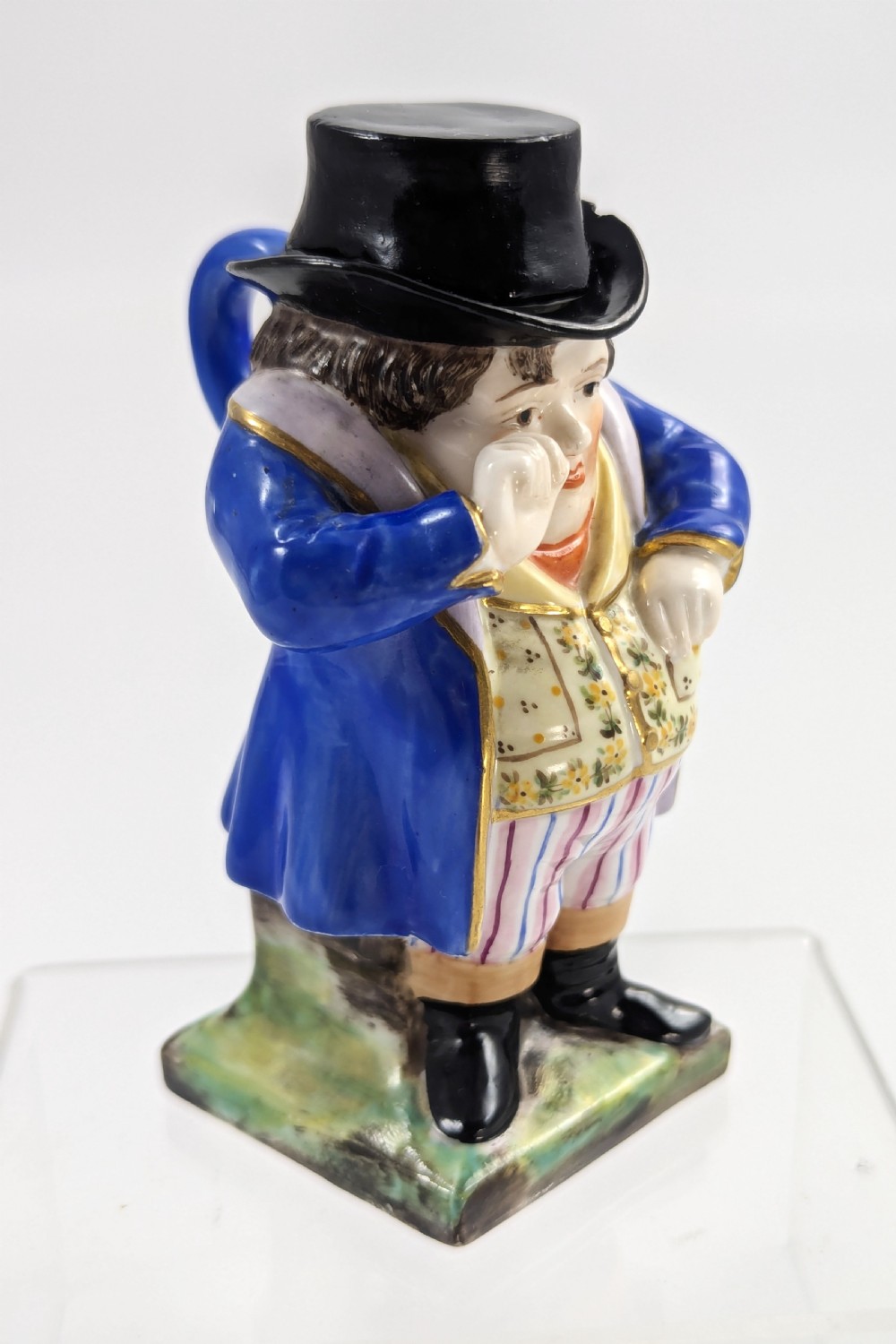 A porcelain Toby jug depicting a gentleman in a black top hat, blue coat, and striped trousers taking snuff. View V