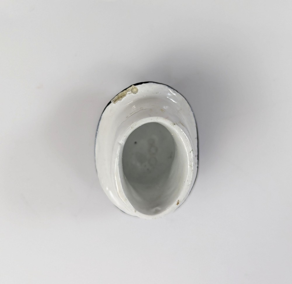 A porcelain Toby jug depicting a gentleman in a black top hat, blue coat, and striped trousers taking snuff. View IX