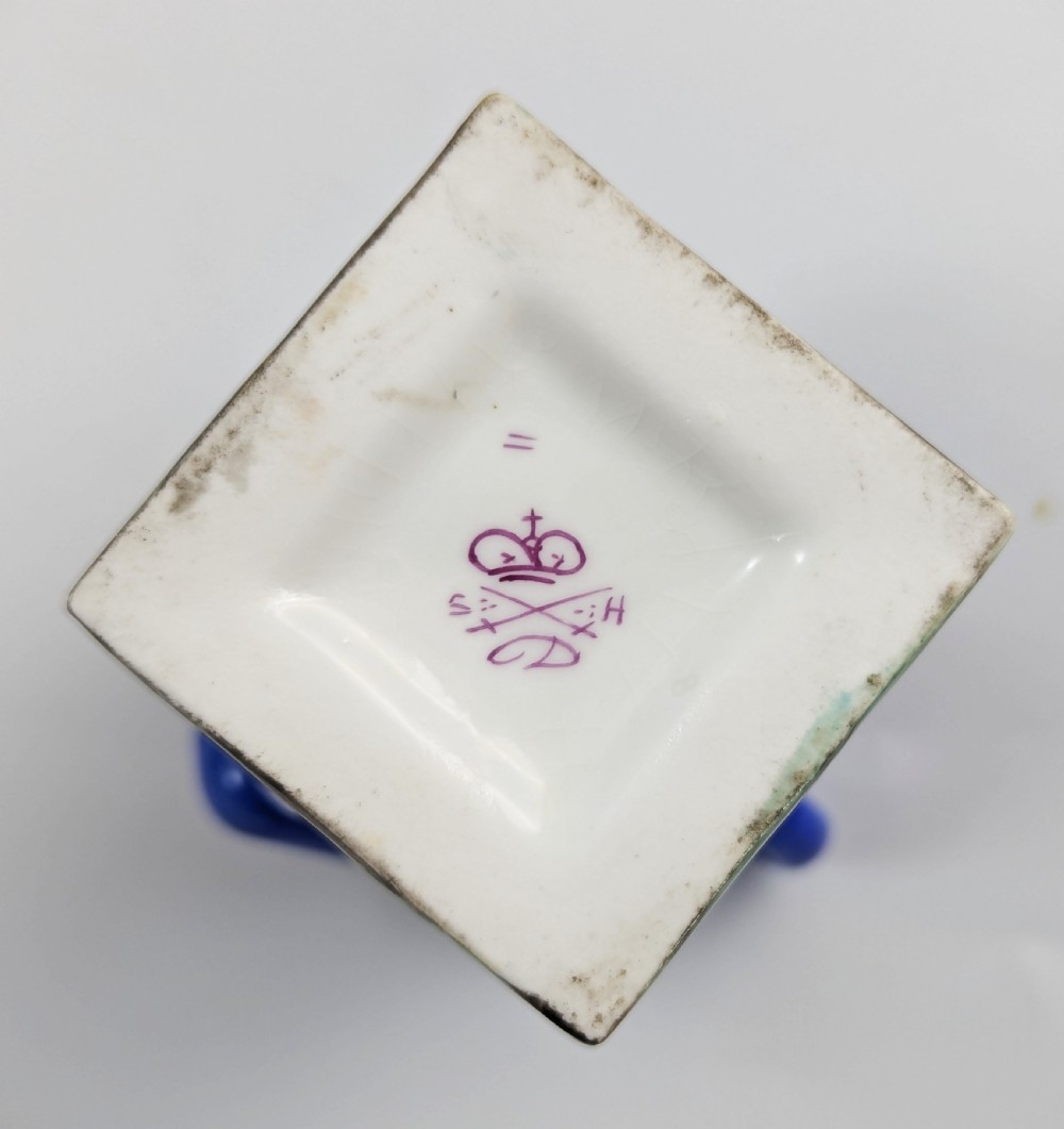 A porcelain Toby jug depicting a gentleman in a black top hat, blue coat, and striped trousers taking snuff. View X