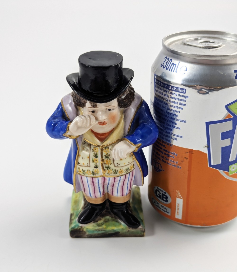 A porcelain Toby jug depicting a gentleman in a black top hat, blue coat, and striped trousers taking snuff. View XI