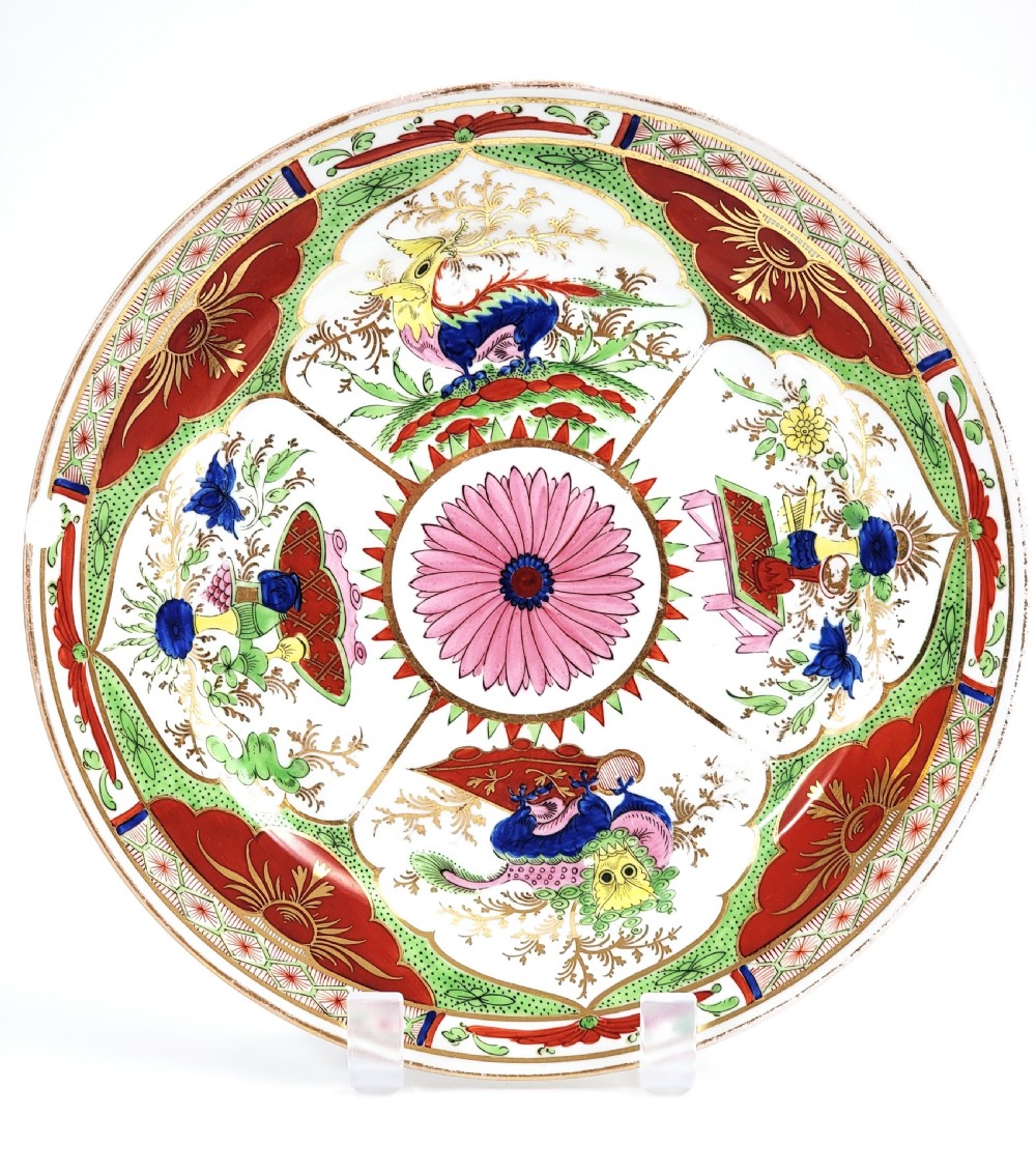 A circular antique English porcelain dessert plate decorated with hand-painted Chinoiserie panels, mythical dragons, and a pink central flower motif.
