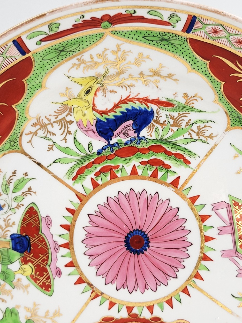 A circular antique English porcelain dessert plate decorated with hand-painted Chinoiserie panels, mythical dragons, and a pink central flower motif. View III
