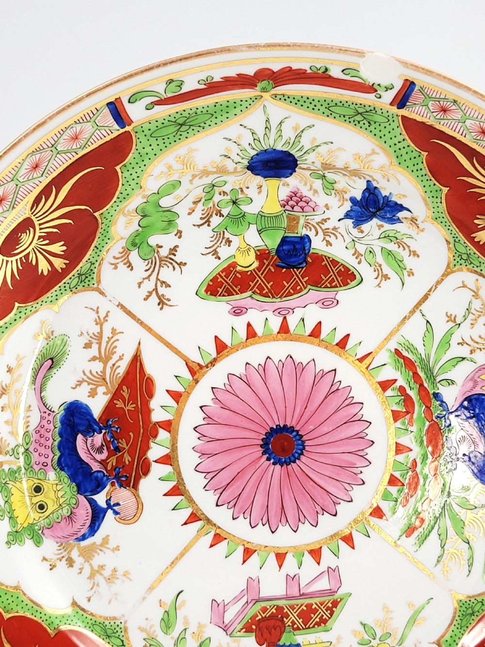 A circular antique English porcelain dessert plate decorated with hand-painted Chinoiserie panels, mythical dragons, and a pink central flower motif. View IV
