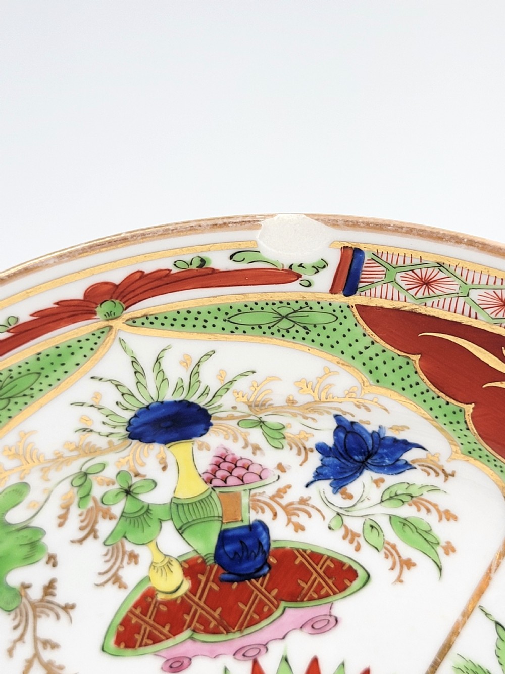 A circular antique English porcelain dessert plate decorated with hand-painted Chinoiserie panels, mythical dragons, and a pink central flower motif. View VII