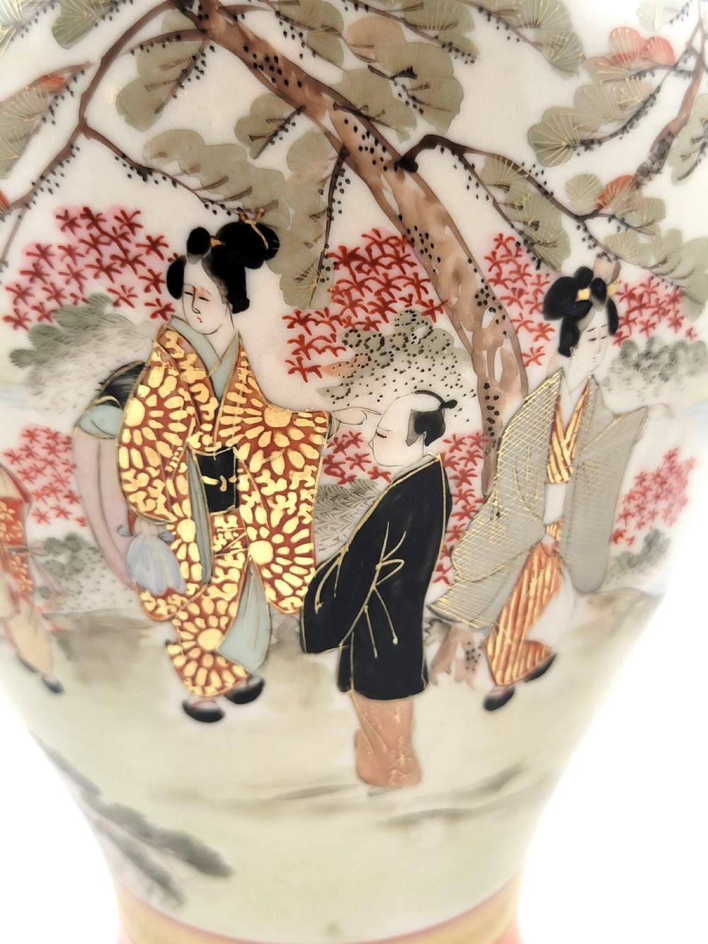 An antique Japanese Kutani porcelain vase featuring hand-painted figures, iron-red flared rim, gilded highlights, moulded lion handles, and a carved wooden display stand. View XIV