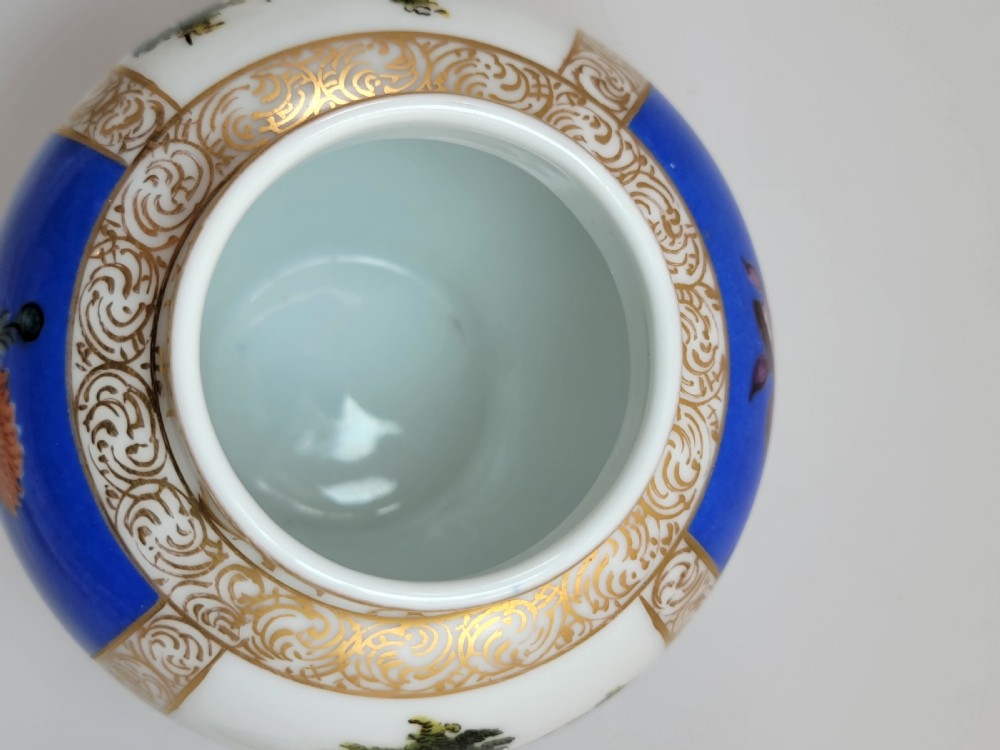 A lidded Dresden porcelain ginger jar featuring hand-painted courting scenes inside gilded cartouches against a cobalt blue ground, topped with a pointed gilt finial. View V