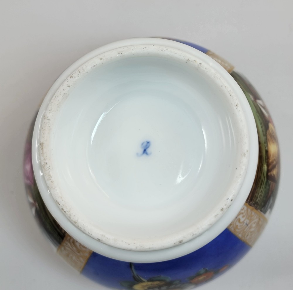 A lidded Dresden porcelain ginger jar featuring hand-painted courting scenes inside gilded cartouches against a cobalt blue ground, topped with a pointed gilt finial. View VI