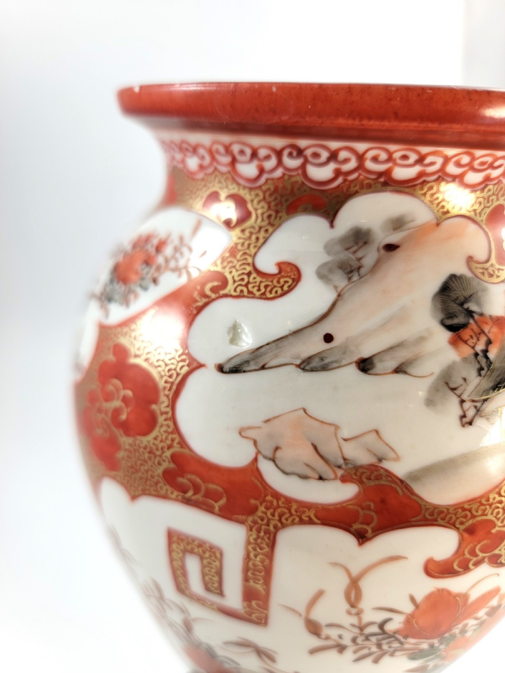 A baluster-shaped Japanese Kutani porcelain vase decorated with red and gold floral motifs on a carved dark wood base. View X