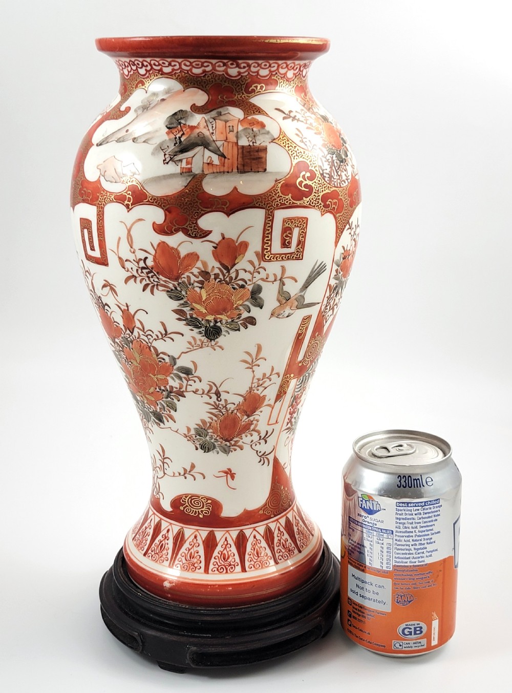 A baluster-shaped Japanese Kutani porcelain vase decorated with red and gold floral motifs on a carved dark wood base. View XI
