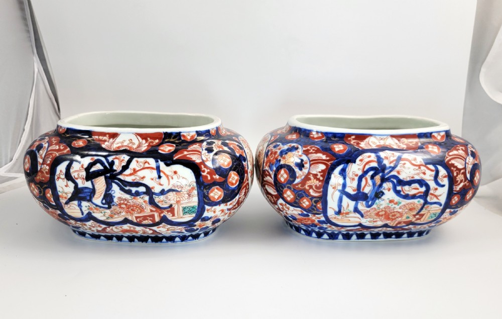 A pair of oval Japanese Imari porcelain jardinieres decorated with cobalt blue, iron red, and floral reserve panels. View IV