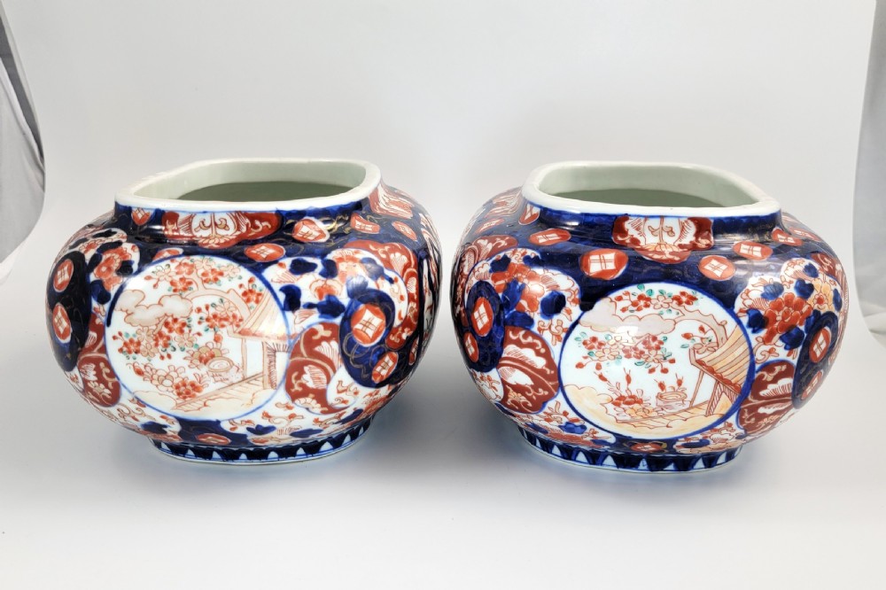 A pair of oval Japanese Imari porcelain jardinieres decorated with cobalt blue, iron red, and floral reserve panels. View V