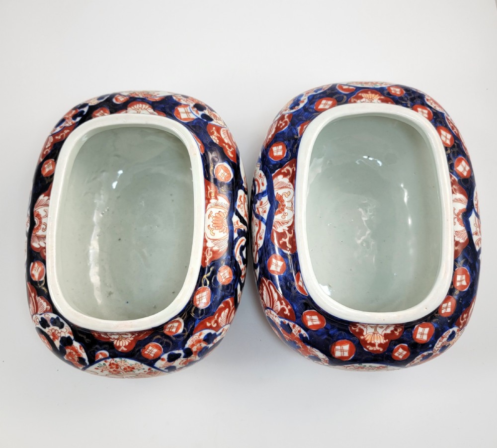 A pair of oval Japanese Imari porcelain jardinieres decorated with cobalt blue, iron red, and floral reserve panels. View VI