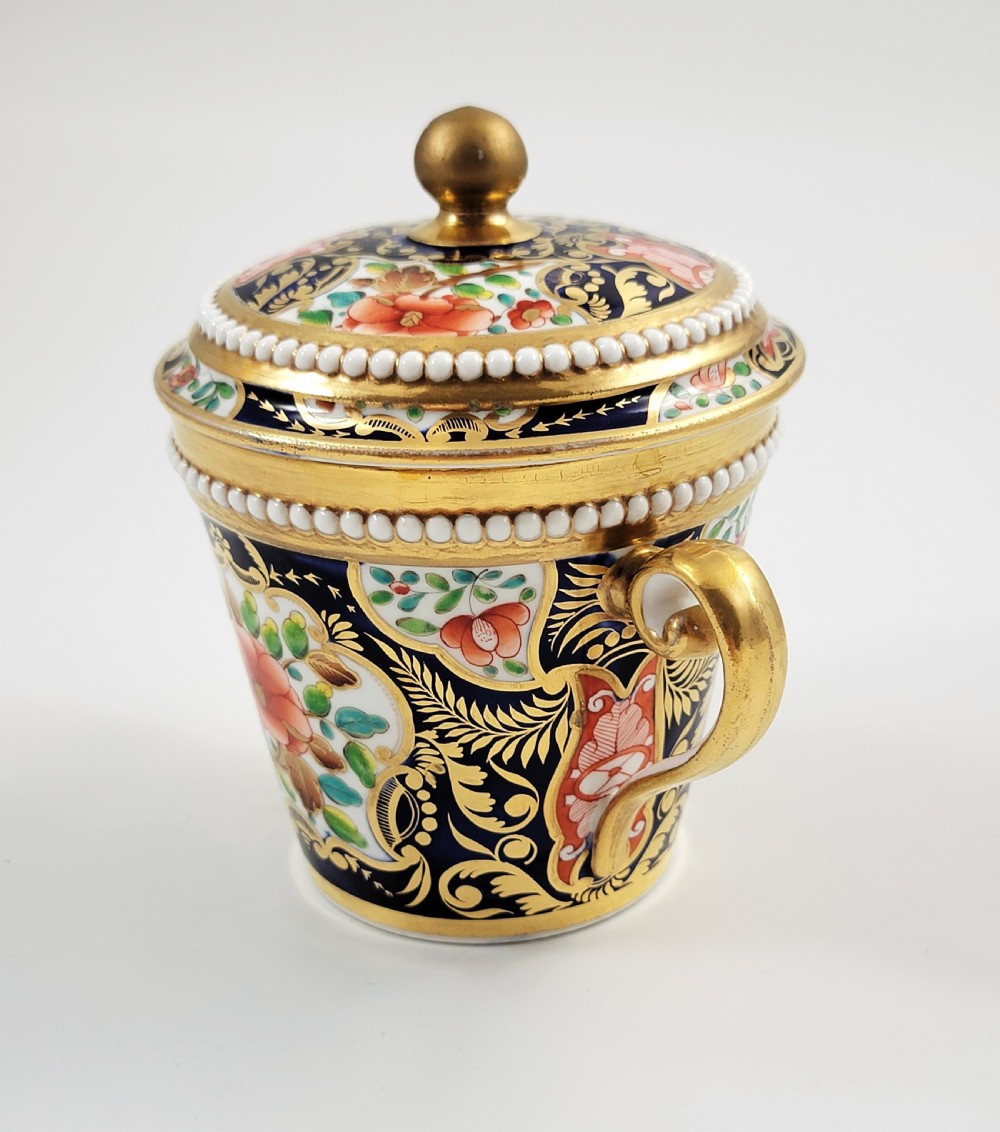 An antique porcelain chocolate cup and lid decorated with cobalt blue and gold Imari floral panels and raised white pearl borders. View II