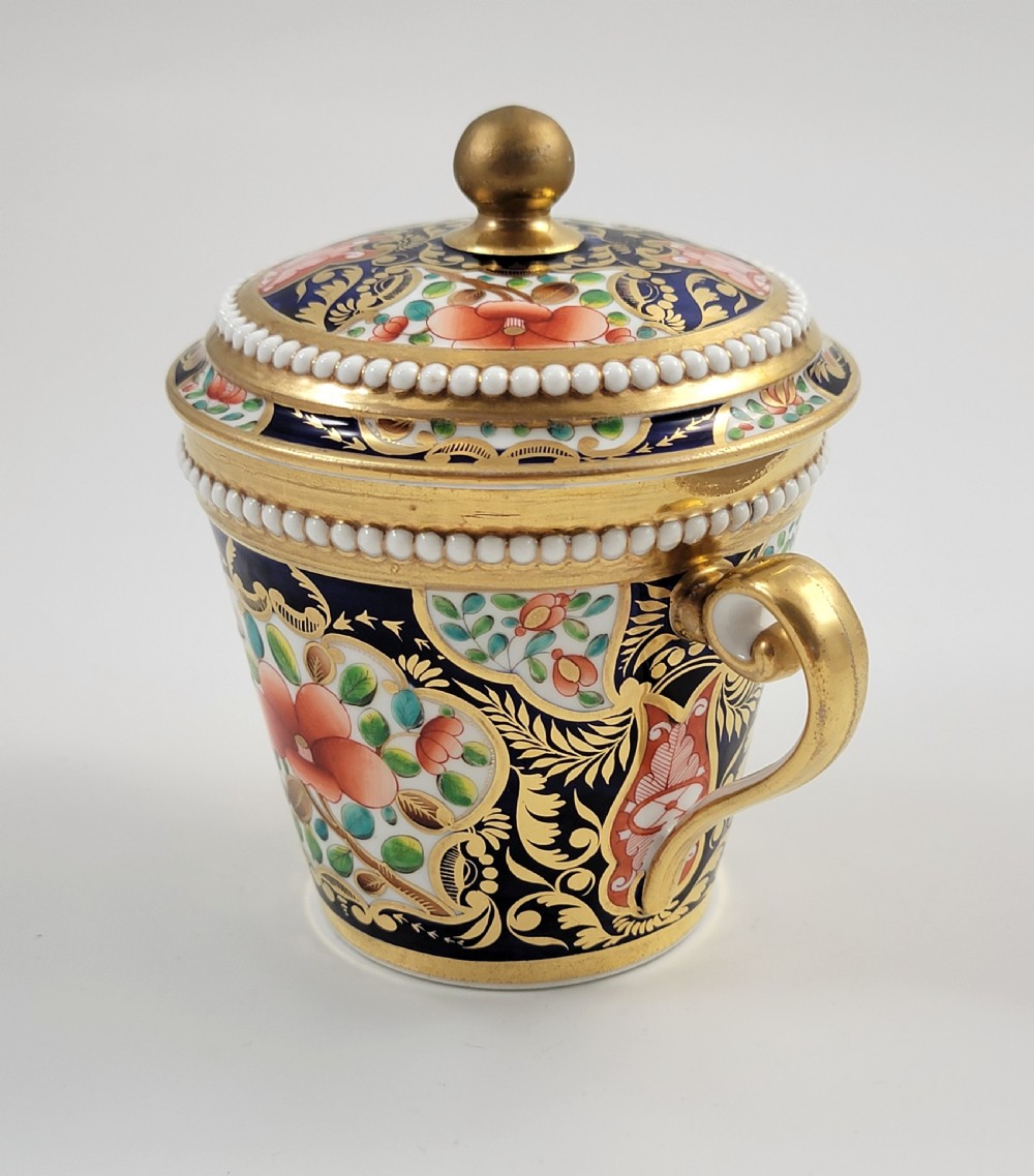 An antique porcelain chocolate cup and lid decorated with cobalt blue and gold Imari floral panels and raised white pearl borders. View V