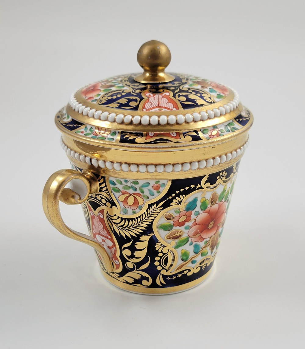 An antique porcelain chocolate cup and lid decorated with cobalt blue and gold Imari floral panels and raised white pearl borders. View VI