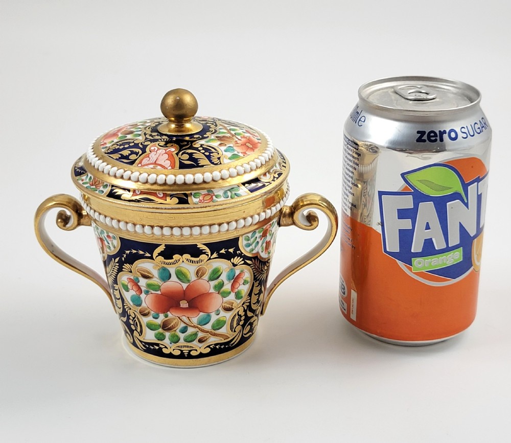An antique porcelain chocolate cup and lid decorated with cobalt blue and gold Imari floral panels and raised white pearl borders. View X