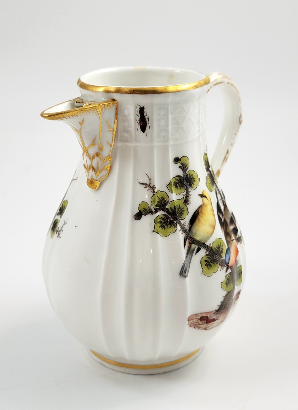 A white ribbed porcelain jug decorated with hand-painted birds, insects, and gilding along the spout and handle. View IV