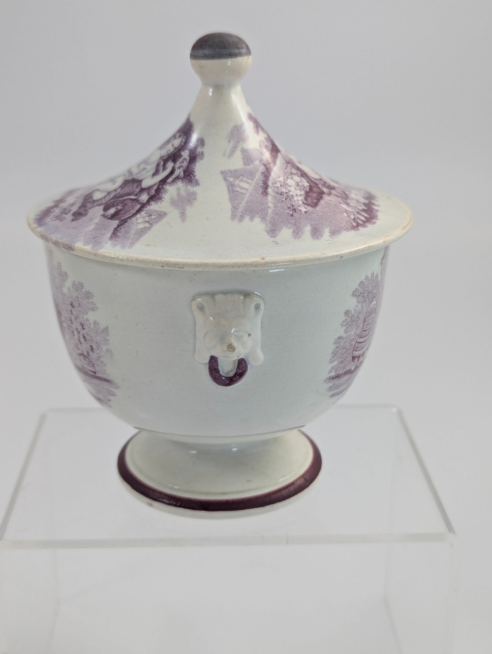 A 19th-century Staffordshire covered earthenware sugar bowl featuring a purple mulberry transferware romantic scene with lion mask handles and a pointed lid. View IV