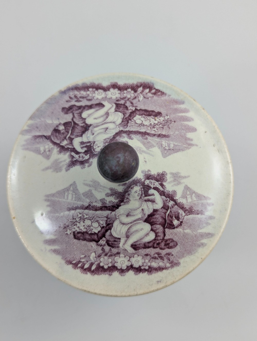 A 19th-century Staffordshire covered earthenware sugar bowl featuring a purple mulberry transferware romantic scene with lion mask handles and a pointed lid. View VI