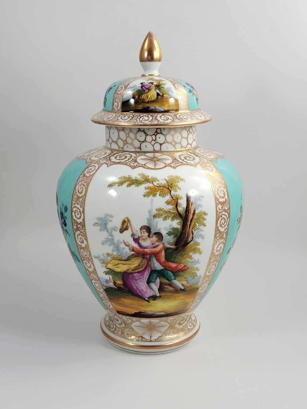A 19th-century Dresden porcelain lidded vase featuring turquoise ground panels, gilded scrollwork, and hand-painted Watteau pastoral scenes. View V