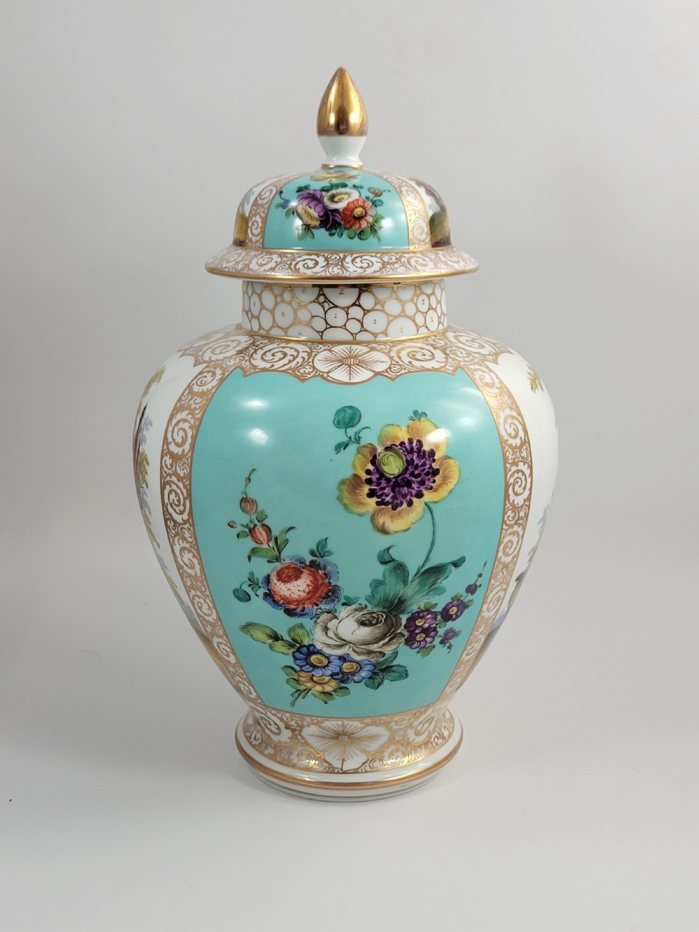 A 19th-century Dresden porcelain lidded vase featuring turquoise ground panels, gilded scrollwork, and hand-painted Watteau pastoral scenes. View VI
