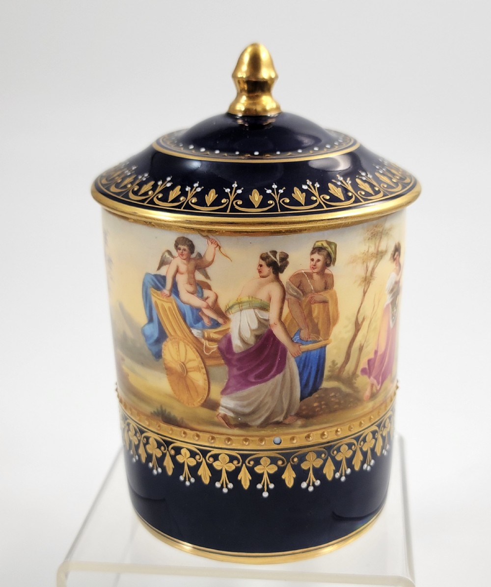 A cobalt blue porcelain covered cup featuring gold leaf scrollwork trim and a hand-painted allegorical woodland vignette with classical figures. View VI