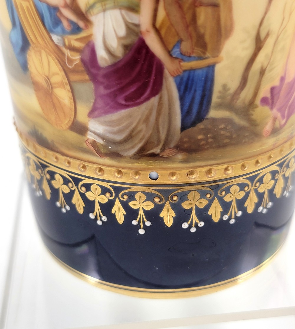 A cobalt blue porcelain covered cup featuring gold leaf scrollwork trim and a hand-painted allegorical woodland vignette with classical figures. View XII