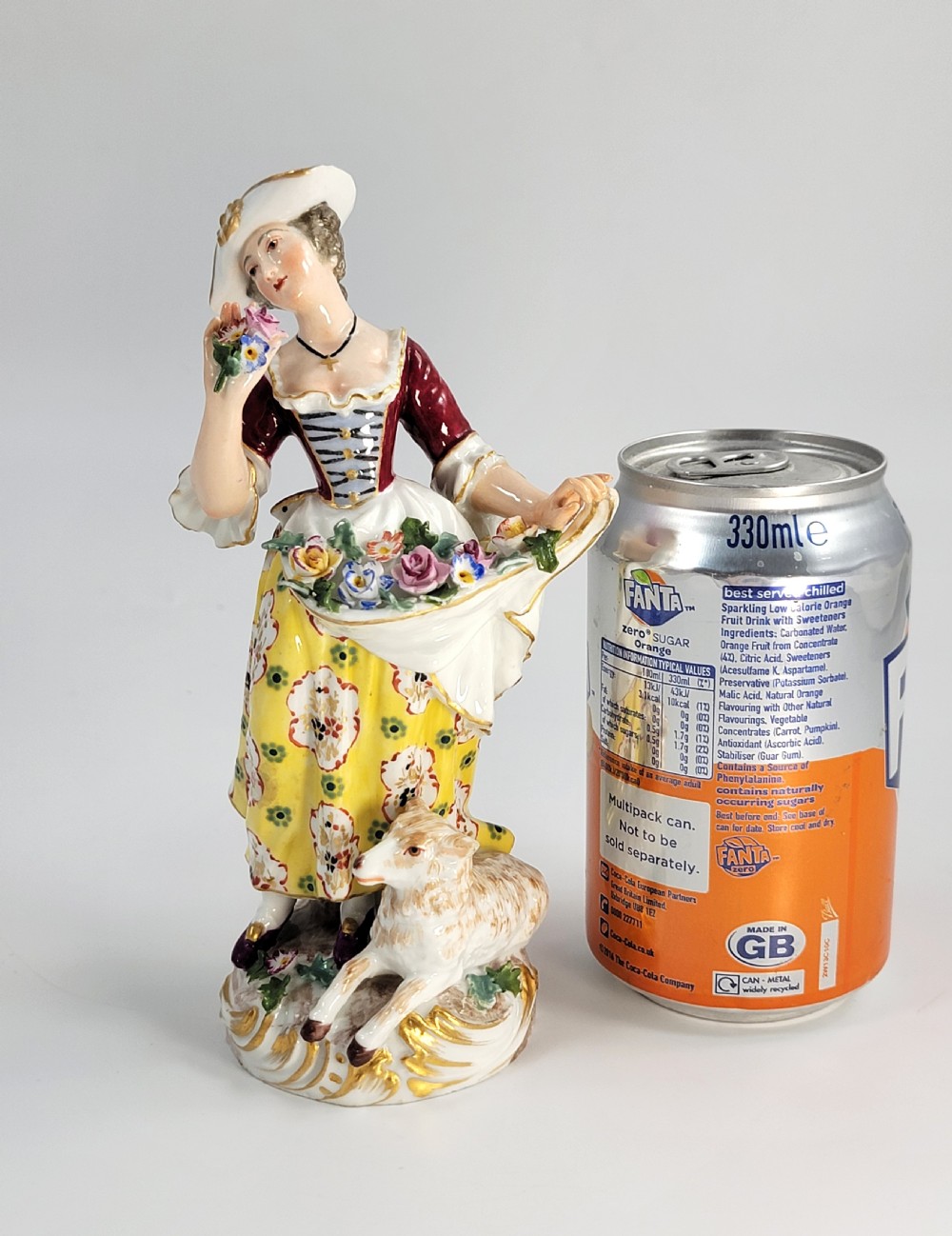 A 19th-century German porcelain figure depicting a shepherdess in a yellow patterned skirt with a lamb resting at her feet. View XI