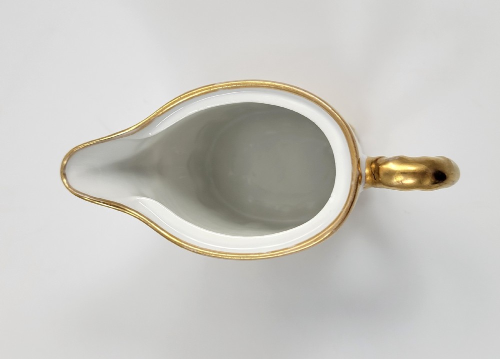 A three-piece white porcelain coffee set featuring a pot, sugar bowl, and cream jug with fluted bodies and gilded acanthus leaf detailing. View XII