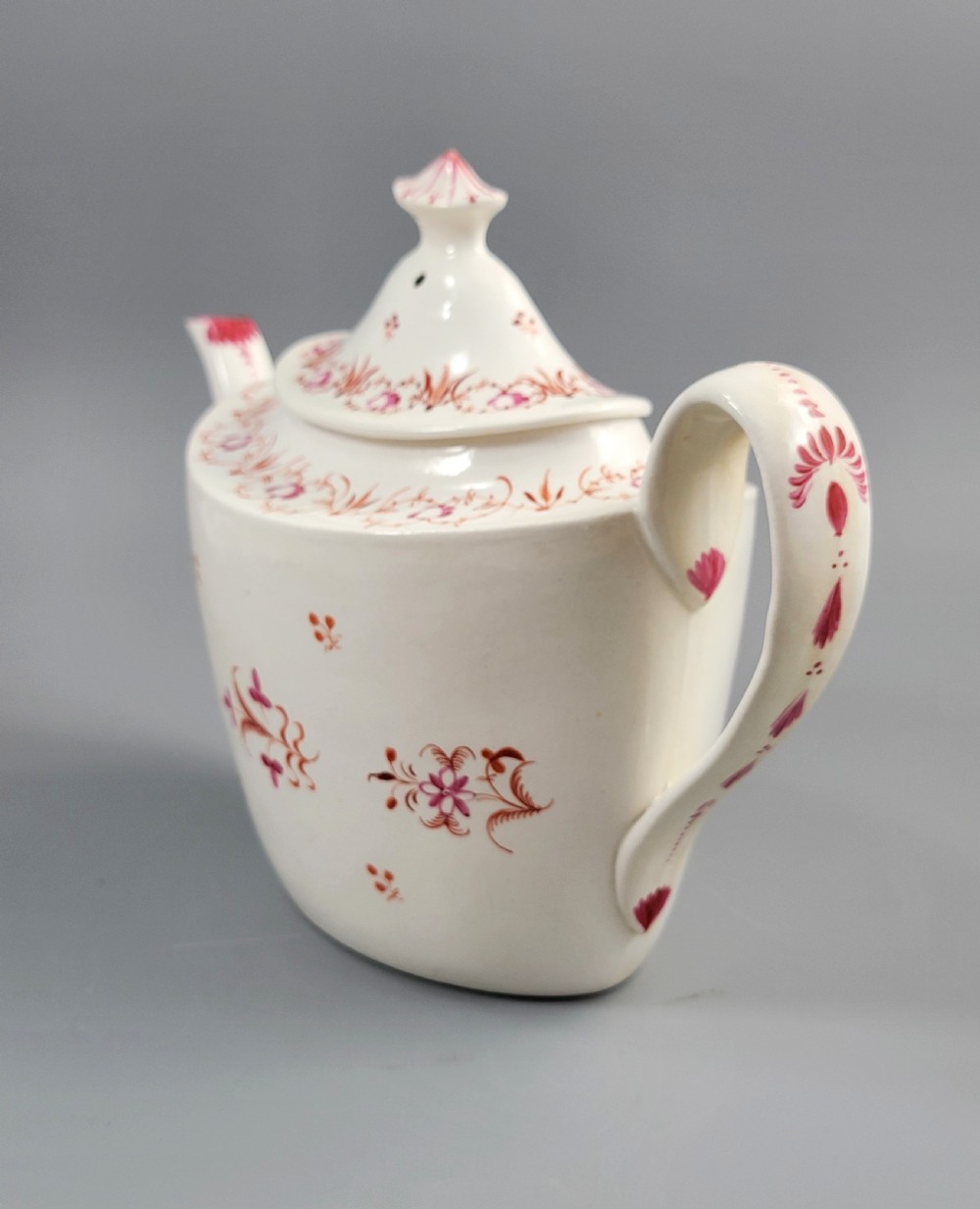 A cream-coloured Georgian porcelain teapot decorated with hand-painted reddish-pink floral sprigs, featuring a high lid with a knop and a curved spout. View II