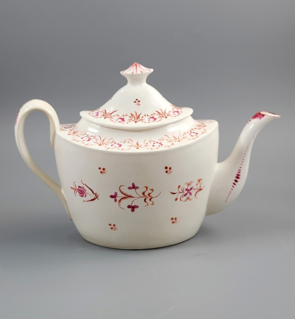 A cream-coloured Georgian porcelain teapot decorated with hand-painted reddish-pink floral sprigs, featuring a high lid with a knop and a curved spout. View IV