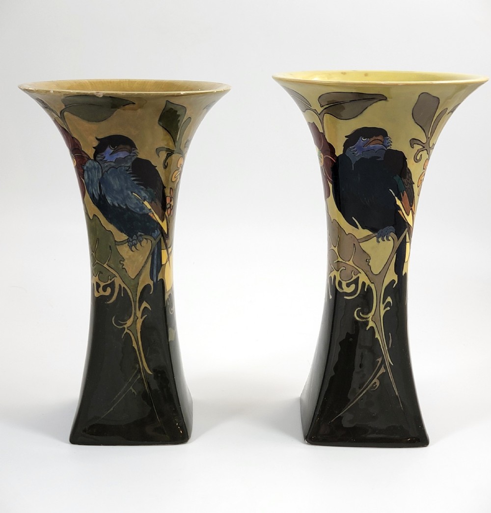 A pair of flared Art Nouveau porcelain vases featuring hand-painted birds perched on branches against a dark brown and yellow background.