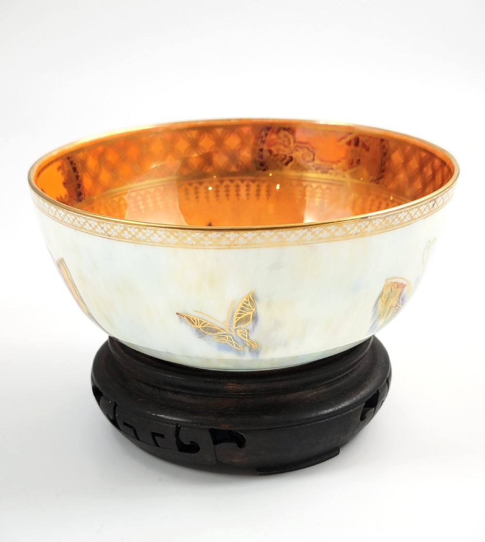 A rounded ceramic lustreware bowl featuring polychrome butterfly illustrations on an iridescent white exterior and an orange gilded interior. View II