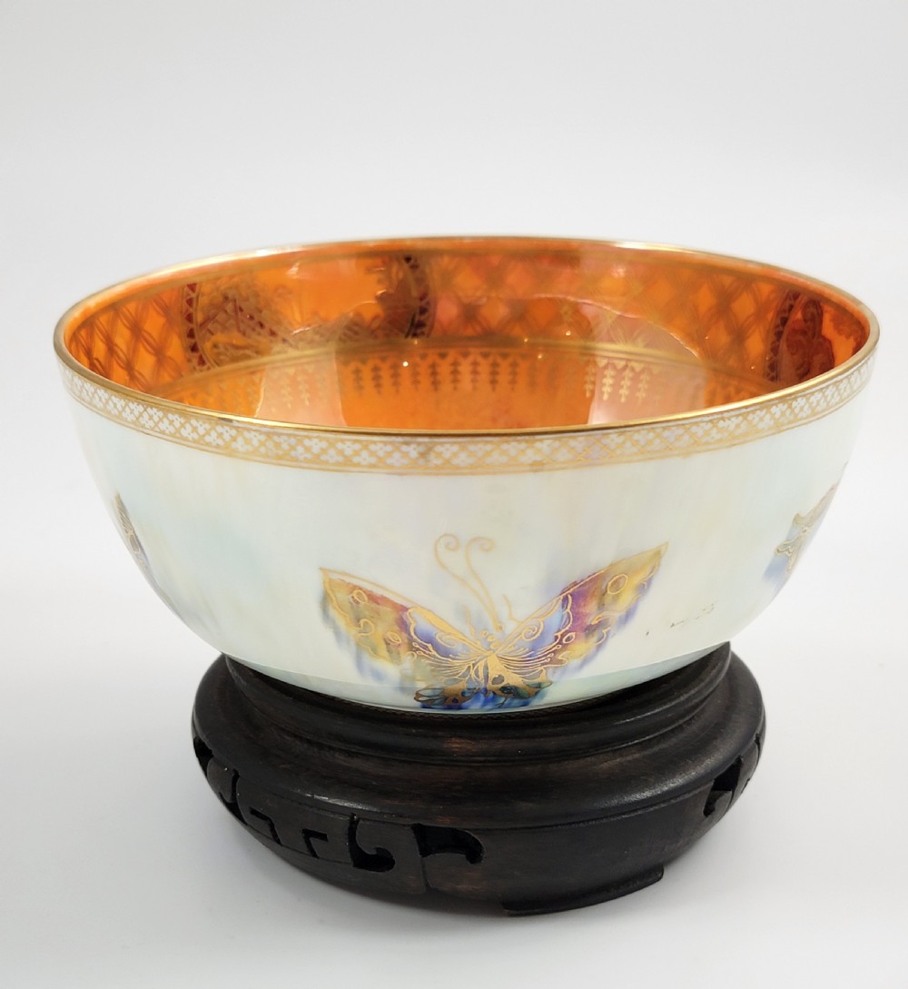 A rounded ceramic lustreware bowl featuring polychrome butterfly illustrations on an iridescent white exterior and an orange gilded interior. View III