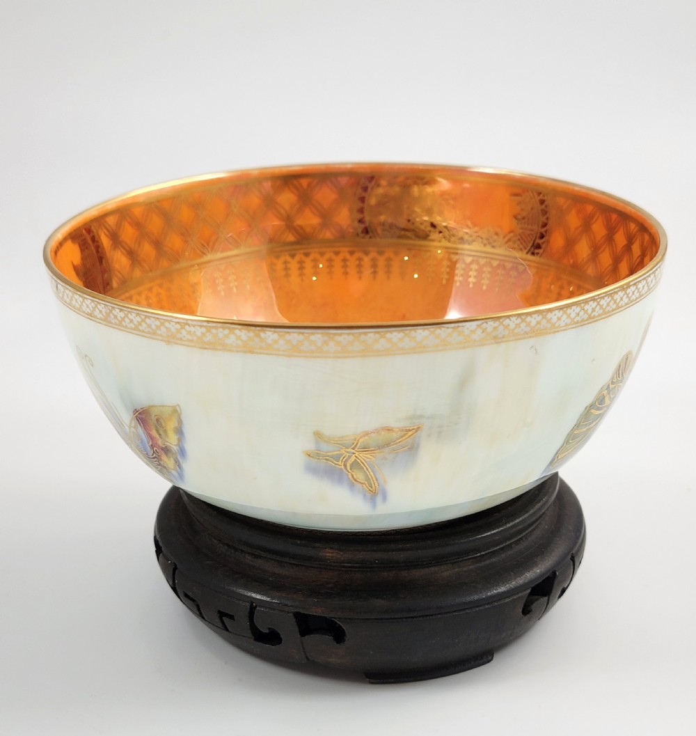 A rounded ceramic lustreware bowl featuring polychrome butterfly illustrations on an iridescent white exterior and an orange gilded interior. View IV