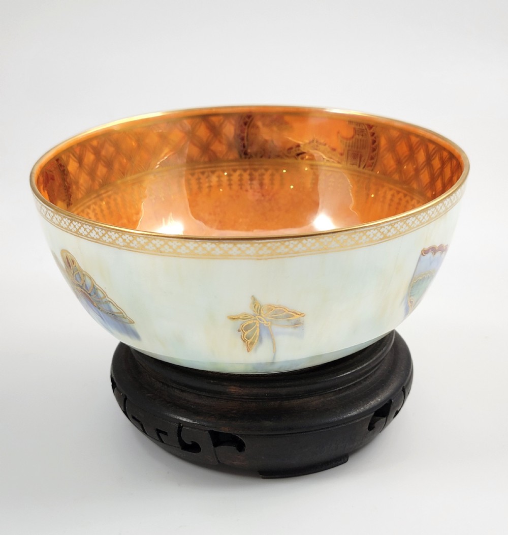 A rounded ceramic lustreware bowl featuring polychrome butterfly illustrations on an iridescent white exterior and an orange gilded interior. View V