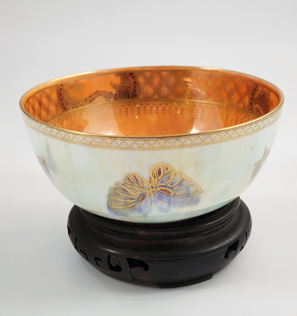 A rounded ceramic lustreware bowl featuring polychrome butterfly illustrations on an iridescent white exterior and an orange gilded interior. View VI