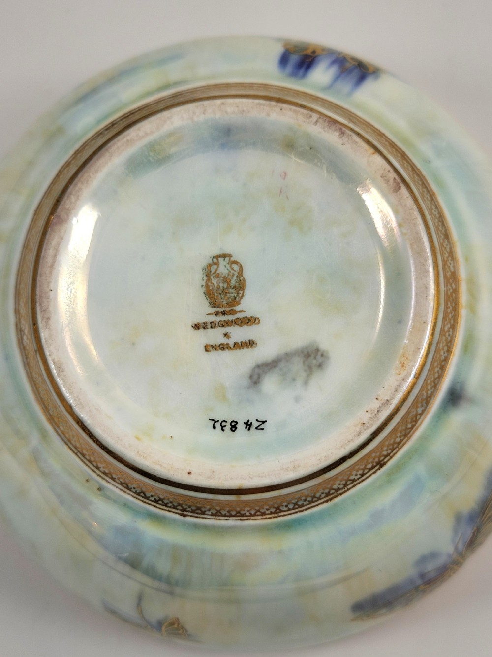 A rounded ceramic lustreware bowl featuring polychrome butterfly illustrations on an iridescent white exterior and an orange gilded interior. View IX