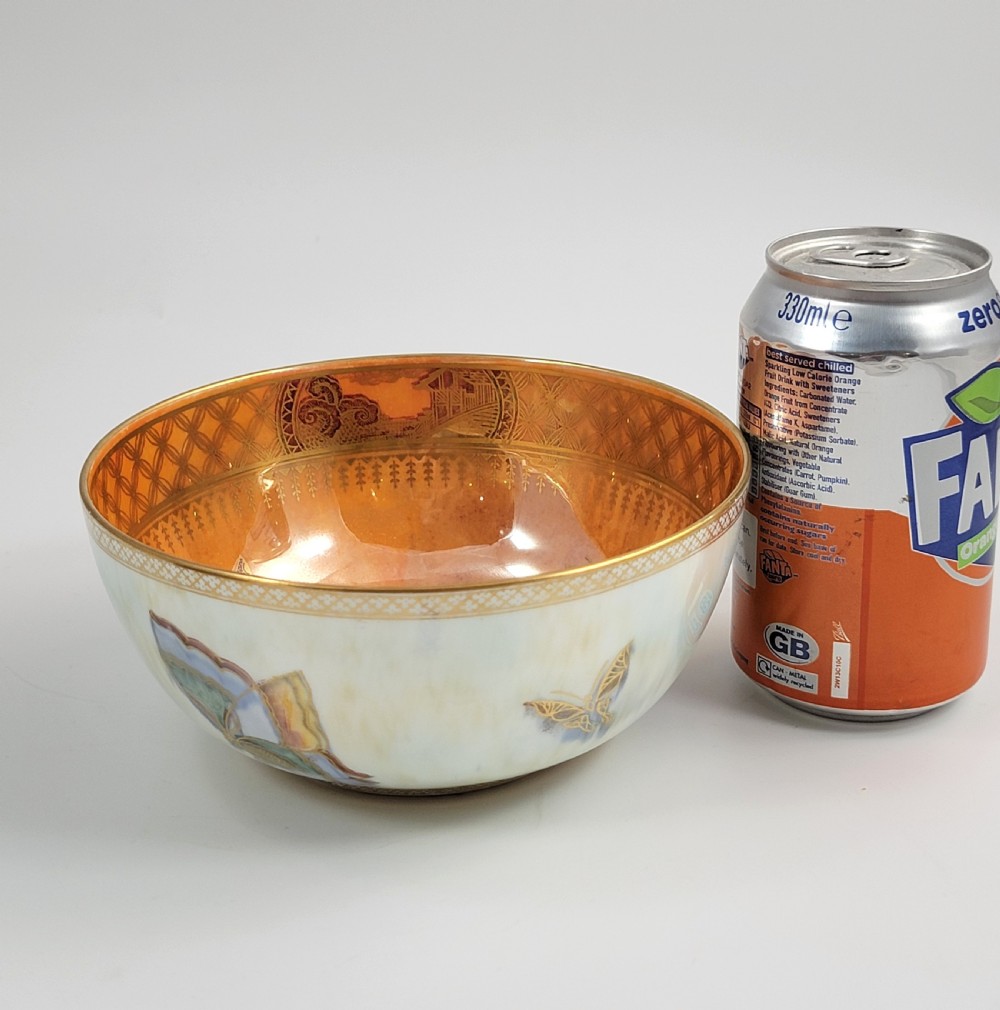 A rounded ceramic lustreware bowl featuring polychrome butterfly illustrations on an iridescent white exterior and an orange gilded interior. View XI