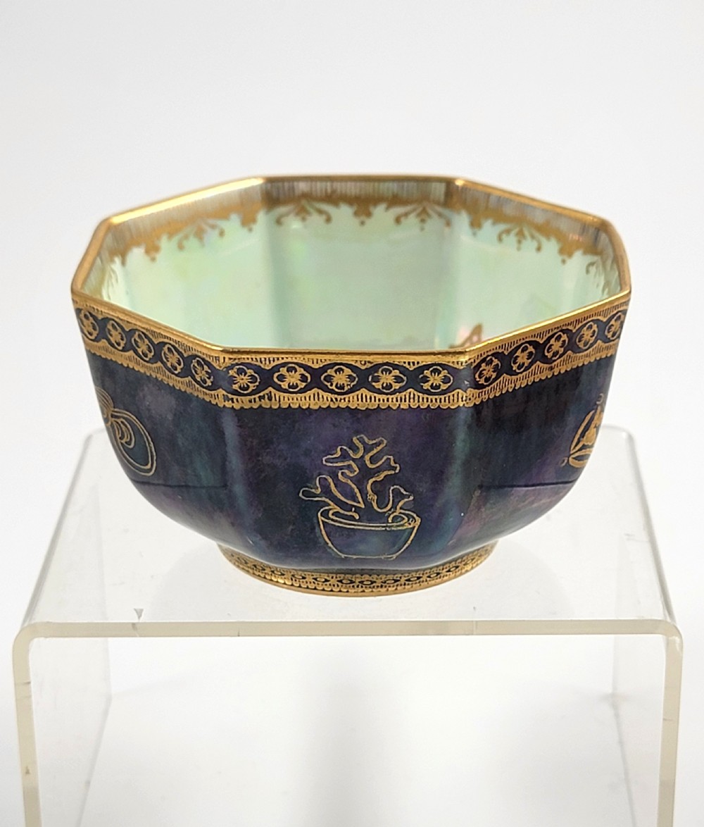 An octagonal porcelain bowl featuring a deep blue iridescent exterior with gilt line drawings and a pale green pearlescent interior.