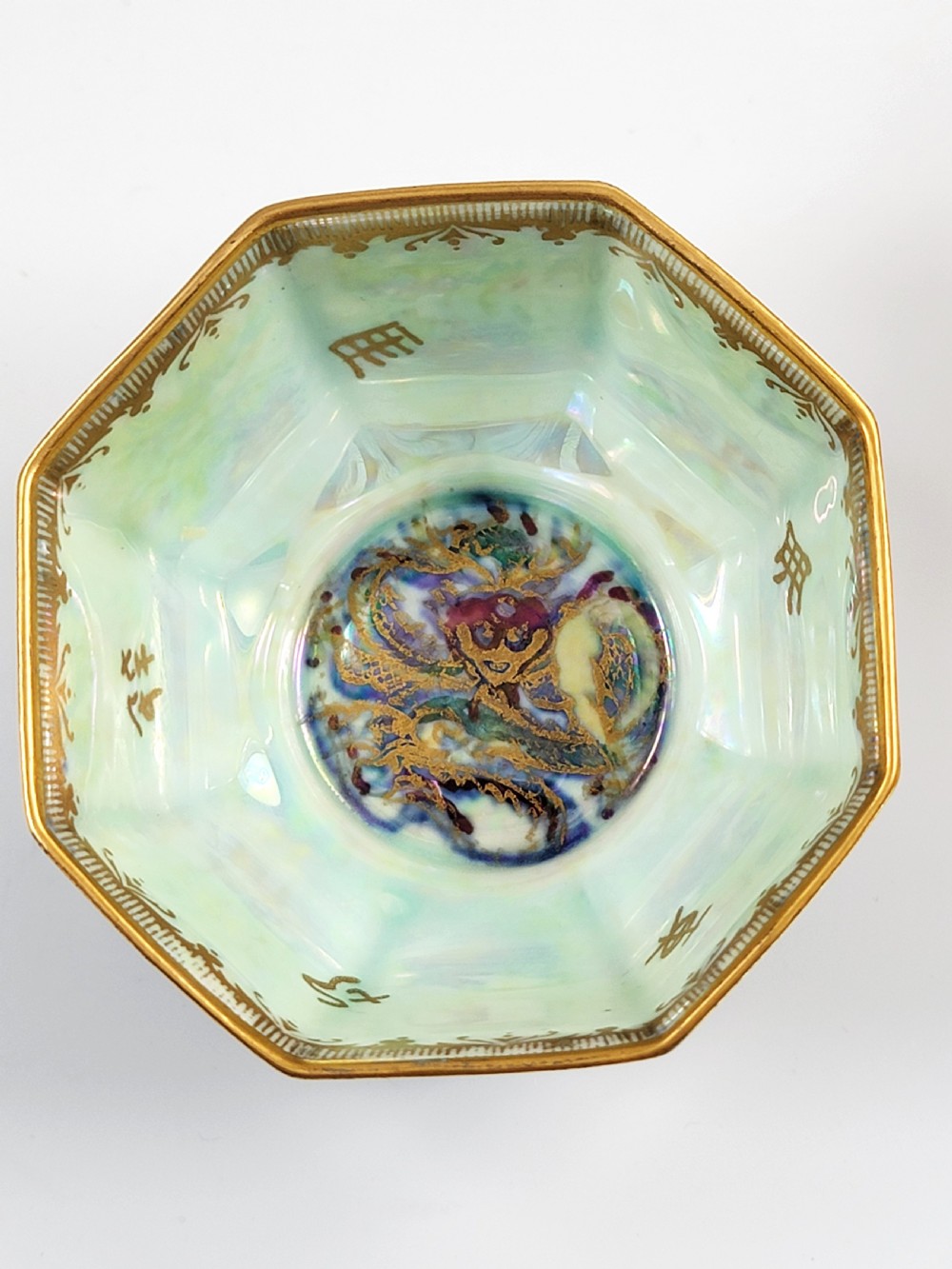 An octagonal porcelain bowl featuring a deep blue iridescent exterior with gilt line drawings and a pale green pearlescent interior. View VI