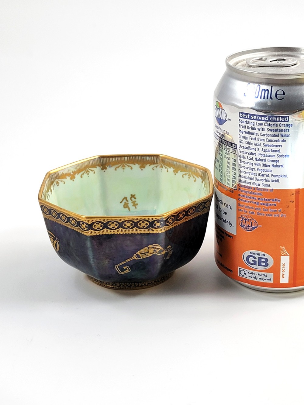An octagonal porcelain bowl featuring a deep blue iridescent exterior with gilt line drawings and a pale green pearlescent interior. View VIII
