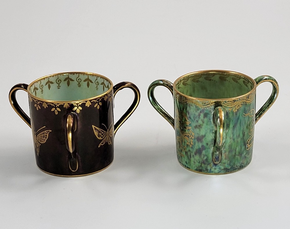 A pair of small three-handled ceramic cups, one in deep purple with a gilded butterfly design and the other in iridescent green with a gilded snake motif. View IV