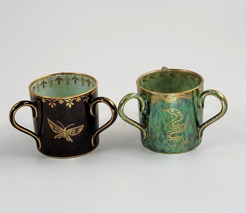 A pair of small three-handled ceramic cups, one in deep purple with a gilded butterfly design and the other in iridescent green with a gilded snake motif. View V