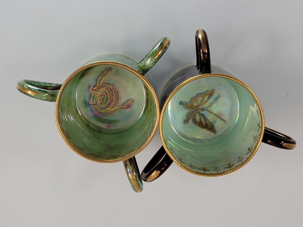 A pair of small three-handled ceramic cups, one in deep purple with a gilded butterfly design and the other in iridescent green with a gilded snake motif. View VI