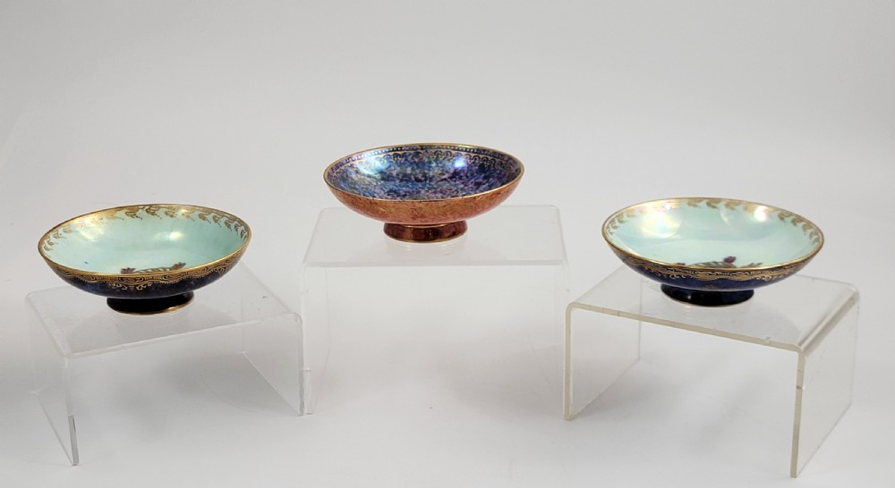 A set of three miniature footed porcelain bowls featuring iridescent lustre glazes in shades of blue, orange, and turquoise, embellished with gilded rim details and central motifs. View II