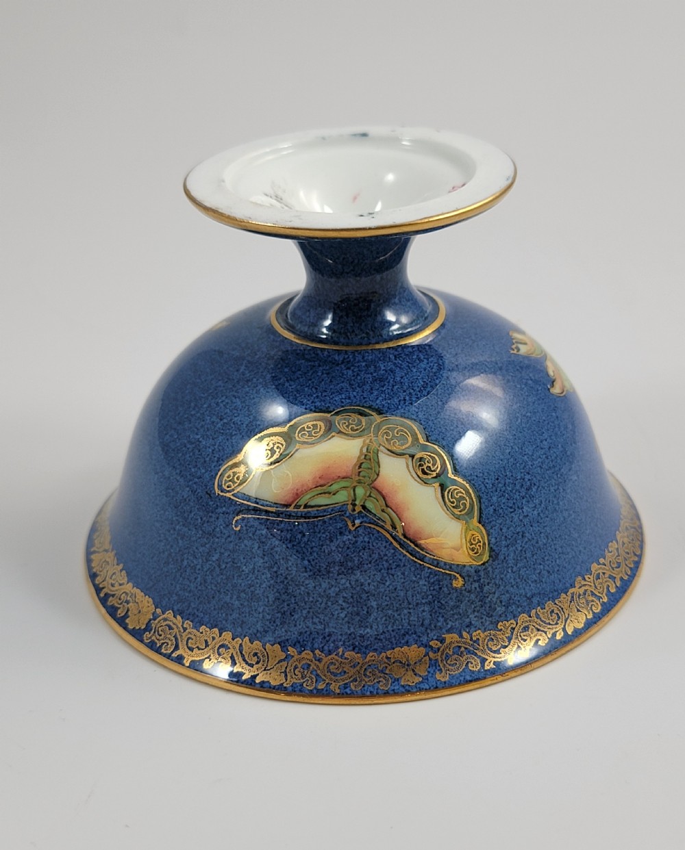 A footed Wedgwood porcelain bowl featuring a deep blue mottled exterior embellished with a gilded butterfly and an iridescent pearlescent interior with gold trim. View XIV