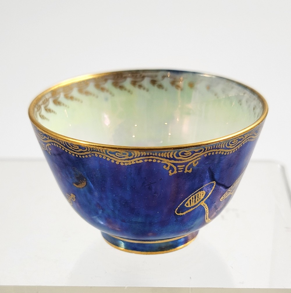 A miniature Wedgwood lustre porcelain cup featuring a cobalt blue iridescent exterior decorated with gilded dragon motifs and a pale iridescent green interior.
